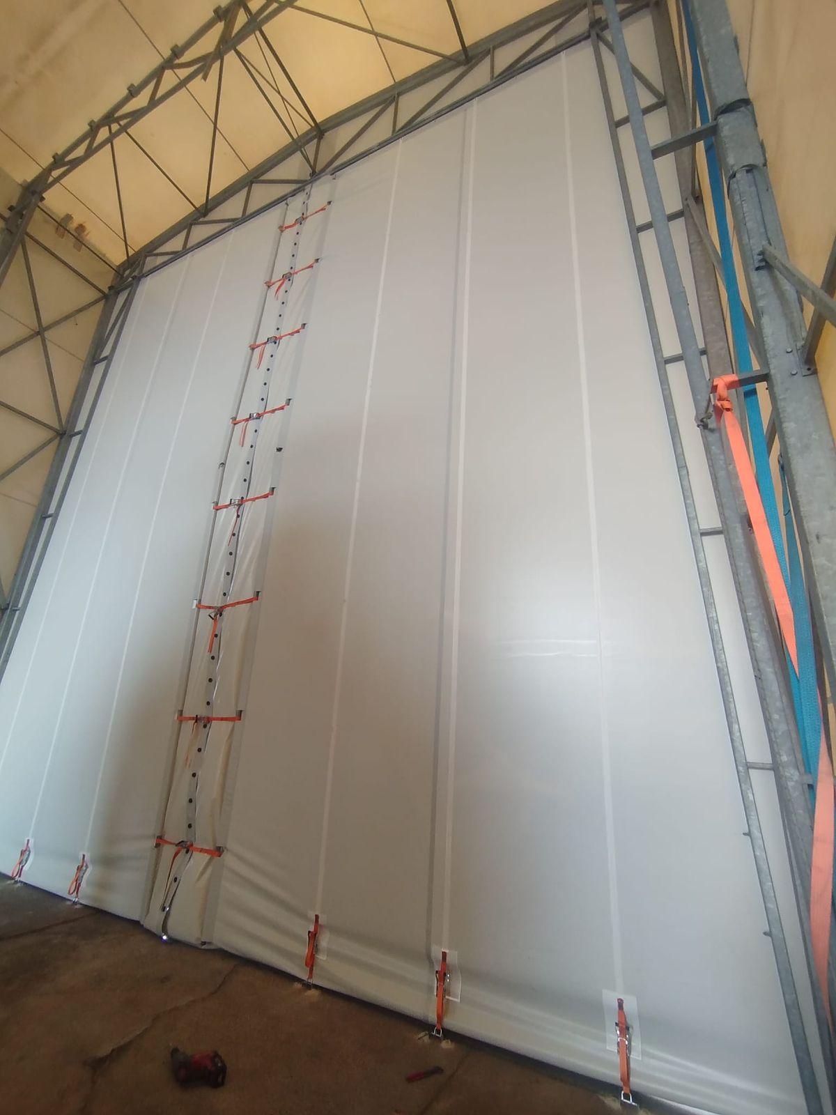 Dettaglio della testata in telo PVC con giunzione centrale chiusa da cinghie a cricchetto arancioni e tensionamento a terra